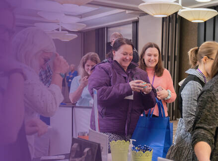 People smiling at exhibitor booths at a conference.